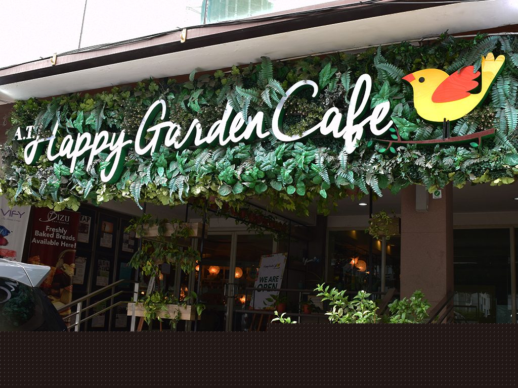 Happy Garden Cafe exterior storefront with green signage surrounded by lush plants at Jupiter Street, Makati